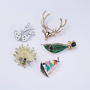 Detailed macro view of enamel animal and flower brooches with rhinestones and pearls