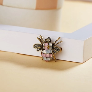 Vintage gold bee brooch with pink rhinestones and black crystals on a warm background