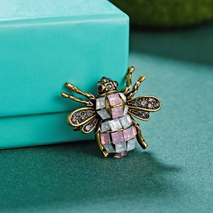 Macro side view of vintage bee brooch with rhinestones on a textured gift box background