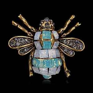 Macro shot of vintage bee brooch with rhinestones and blue crystals on black background