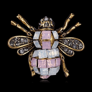 Macro detail of vintage gold bee brooch with rhinestones and pink and blue gemstones