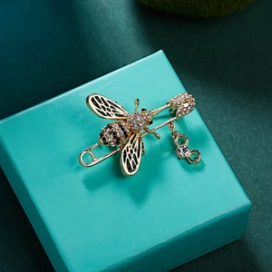 Détail de la broche abeille avec strass, ailes émaillées et pendentif nid d'abeille