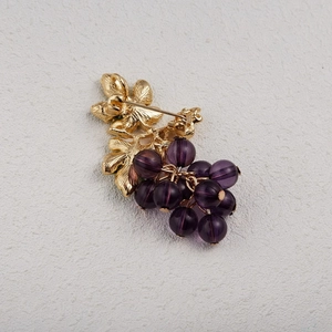 Vue détaillée de l'arrière d'une broche raisin dorée avec fermoir sécurisé et détails de feuilles