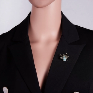 Detail of vintage bee brooch with blue rhinestones pinned on a black suit lapel