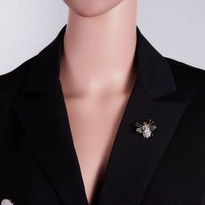 Close-up of a vintage bee brooch with pink mosaic texture on a black suit jacket