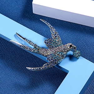 Detailansicht einer eleganten Schwalbenbrosche mit blauen Kristallen und Perlenverzierung