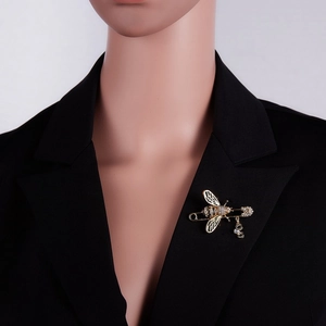 Vue détaillée d'une broche abeille dorée ornée de strass sur le revers d'un blazer noir