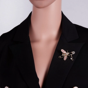Détail de la broche abeille avec ailes en émail rouge et cristaux sur veste noire