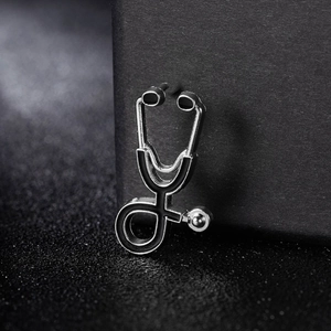 Close-up of a silver-tone stethoscope earring featuring black oil drip details