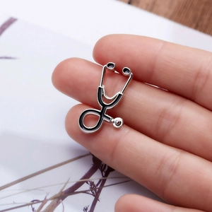 Fashionable silver stethoscope brooch with black enamel inlay held in hand