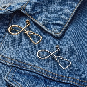Detail of silver and gold stethoscope brooches pinned on blue denim fabric texture
