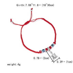 Detail view of red braided bracelet with evil eye beads and silver turtle charm