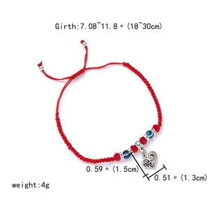 Detail showing adjustable red braided rope bracelet with blue evil eye bead and silver heart