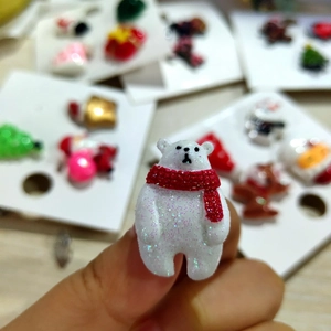Detail shot of a polar bear brooch with sparkling white glitter and a red scarf accessory