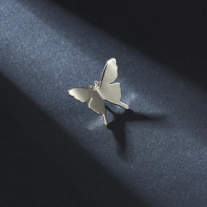 Close-up of golden metal butterfly brooch with polished finish and dramatic lighting