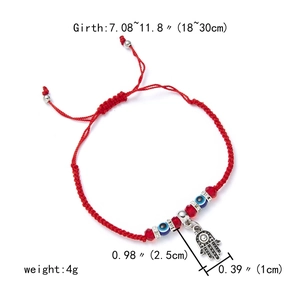 Detail of red braided string bracelet with Hamsa Hand charm and blue evil eye beads