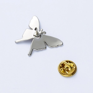 Macro detail of silver butterfly lapel pin back with golden clutch closure components