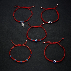 Detail of five handmade red string evil eye bracelets with hamsa hand charms and beads