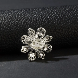 Dettaglio del retro della spilla a fiore con metallo argentato traforato e chiusura
