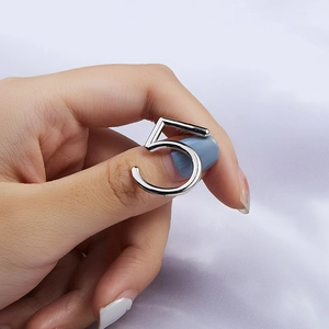 Detailed view of silver number 5 ring on hand with elegant white fabric background