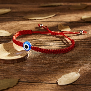 Detailed close-up of woven red evil eye bracelet with adjustable silver metal beads