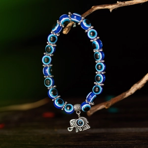 Blue Evil Eye beaded bracelet with silver elephant charm on a rustic branch display