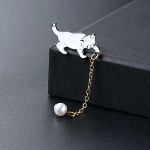 Elegante witte emaille kattenbroche met gouden ketting en parel op een luxe sieradendoos