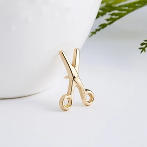 Detailed close-up of creative golden scissor brooch with a high-polished metallic finish