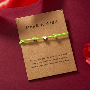 Nahaufnahme eines neongrünen Herz-Armbands auf einer Make a Wish Kraftkarte