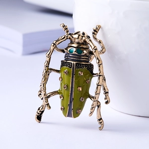 Detailed close-up of vintage gold beetle brooch with green enamel and brown rhinestones
