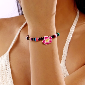 Colorful tropical beaded bracelet featuring black crystals and pink plumeria flower charm