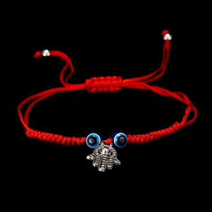 Detailed macro view of the Hamsa Hand and blue Evil Eye charm on red woven bracelet