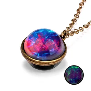 Macro detail of bronze galaxy pendant necklace showing red-blue nebula and green glow effect