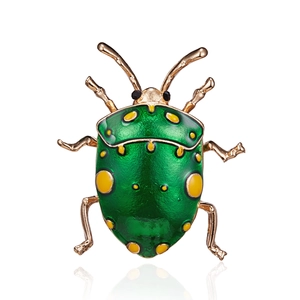 Close-up of a green beetle brooch with yellow spots and golden alloy insect legs