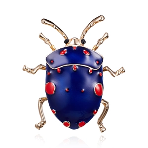 Detailed close-up of a blue and red enamel beetle brooch with gold-plated finish