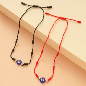Detail van rood en zwart gevlochten evil eye armbanden met gouden kralen op blokken