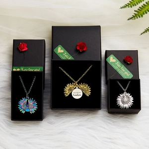 Close-up of three sunflower locket necklaces in gift boxes with engraved sunshine text
