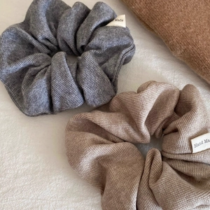 Close-up of gray and coffee knitted scrunchies with Hand Made label detail