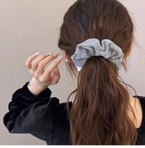 Detail of grey knitted scrunchie showing fabric texture on a ponytail hairstyle