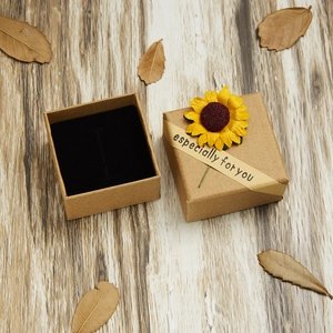 Close-up of kraft jewelry box with sunflower decor on a rustic wood background