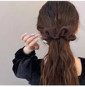 Rear view of model wearing a soft dark brown knit scrunchie with a bow detail on a ponytail