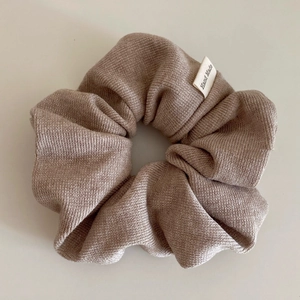 Detail of beige knitted scrunchie with soft texture and Hand Made fabric label