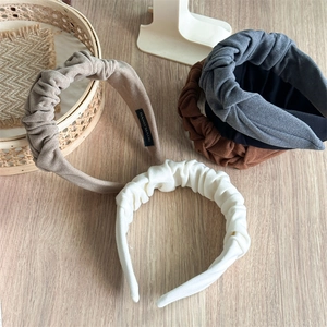Detailed view of pleated fabric headbands in assorted colors on a wooden surface