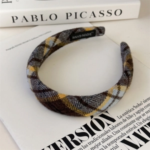 Detail showing handmade plaid fabric headband texture with a woven label on books