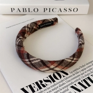 Detail shot of a plaid headband featuring a hand made tag on a stylish art book