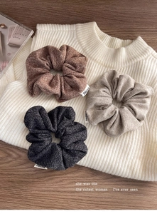 Détail de trois chouchous texturés aux tons café, blé et gris anthracite sur tricot