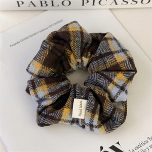 Close-up of a plaid fabric scrunchie with a Hand Made label on a stylish magazine