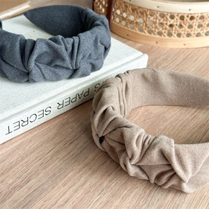 Close-up of pleated fabric headbands in dark grey and light brown with soft texture