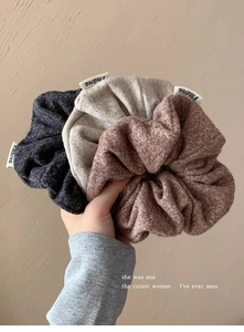 Gros plan de chouchous en maille gris, beige et marron avec étiquettes tissées
