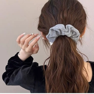 Soft grey knitted scrunchie with textured vertical stripes on brown wavy hair